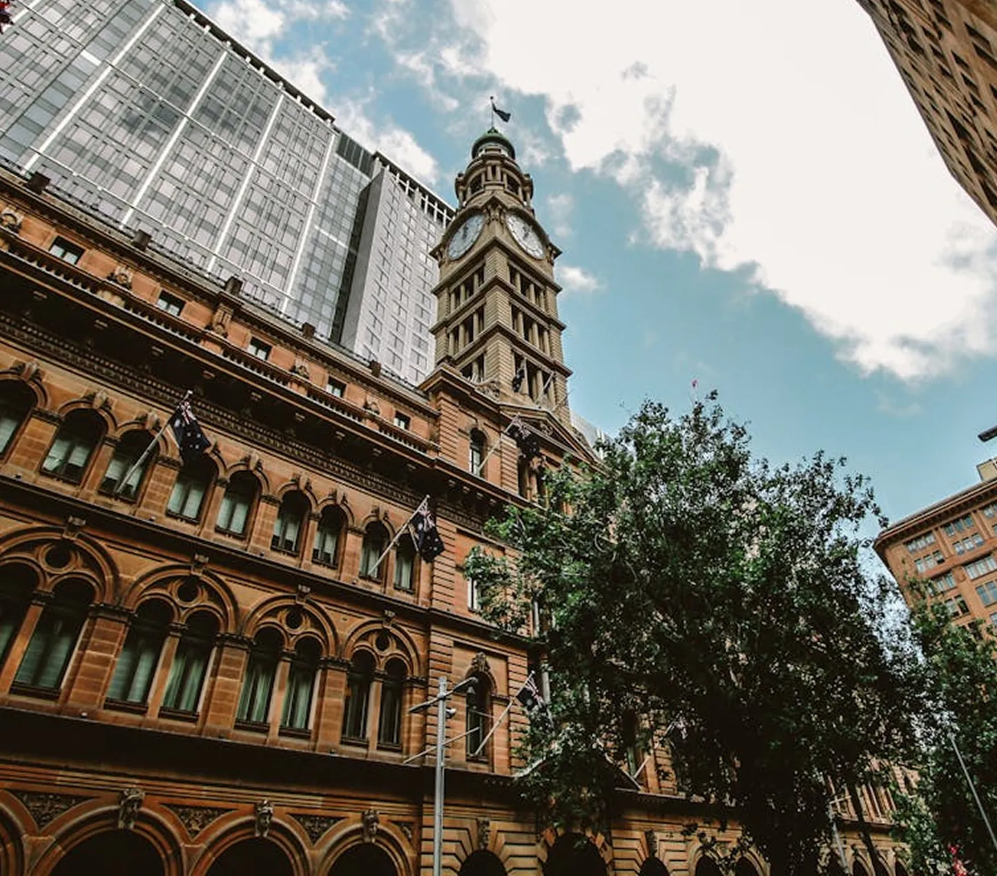 Historic sandstone clock tower among city office buildings