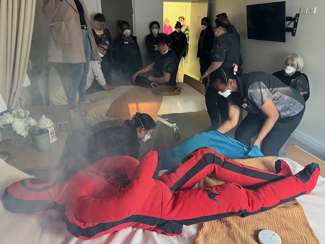 Aged care staff practising an evacuation with a training mannequin in a smoke-filled room