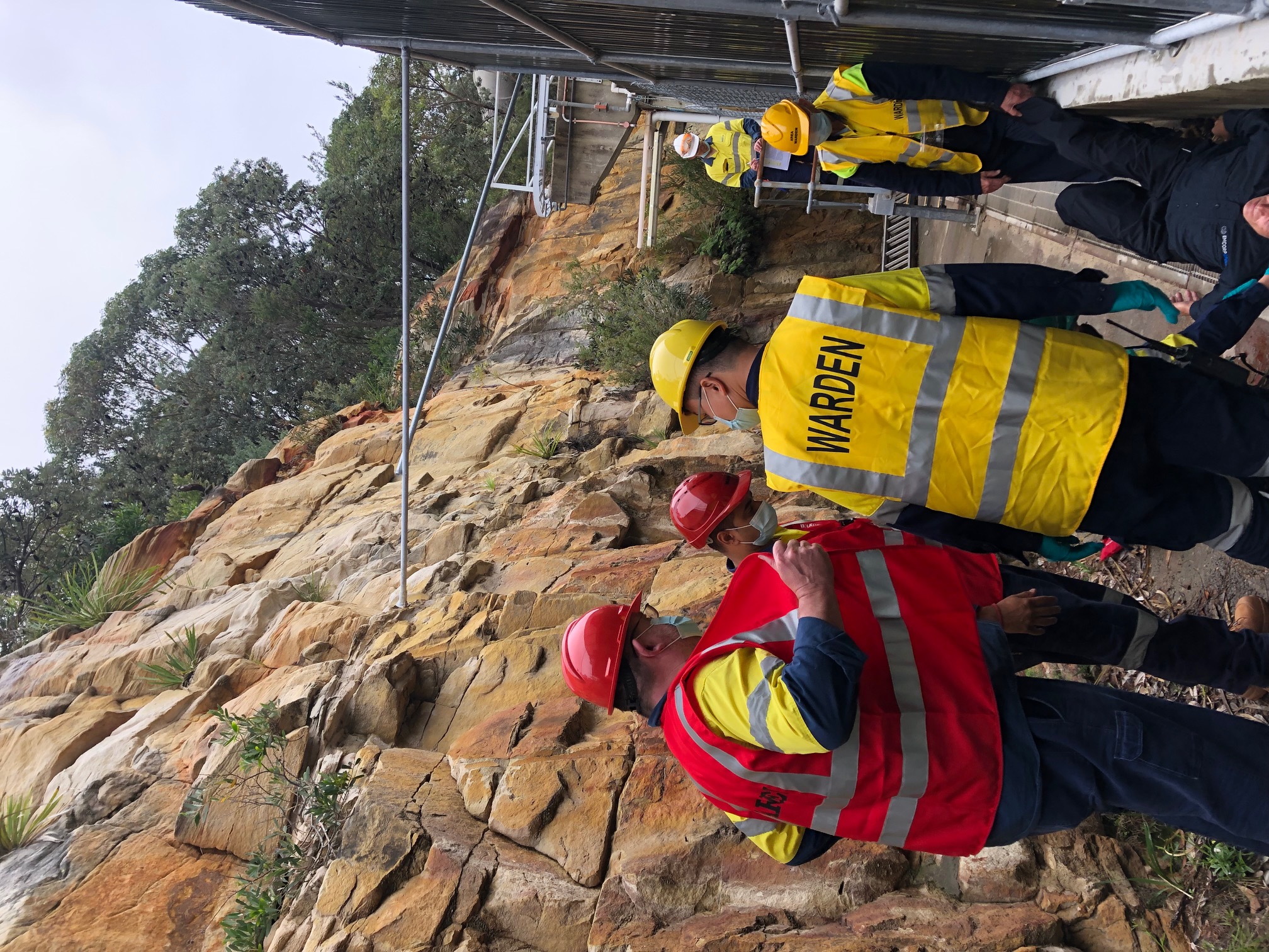 Wardens in hard hats moving along a rock cutting during an emergency exercise