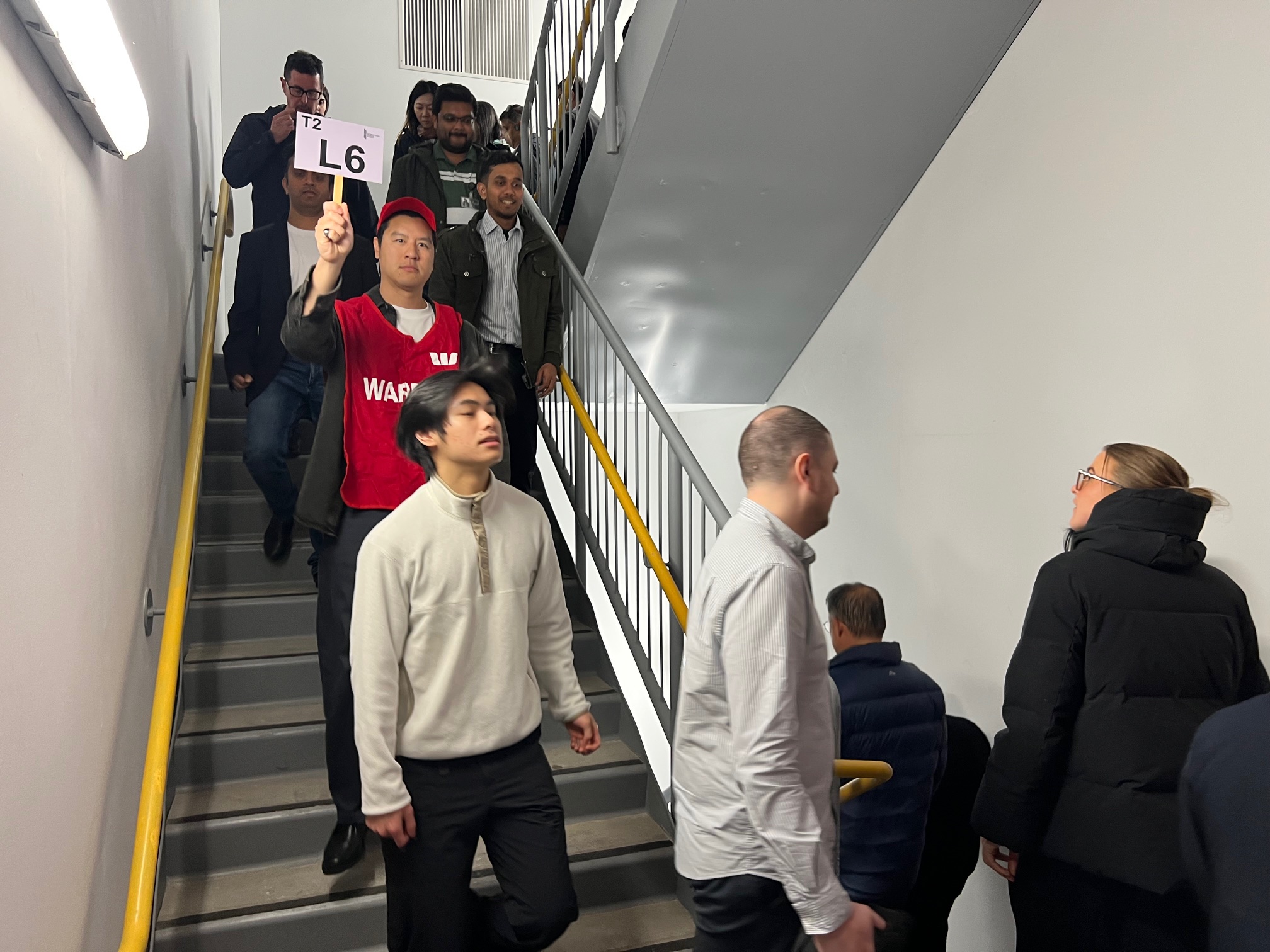 Wardens in red vests leading staff down a fire stairwell during an evacuation drill