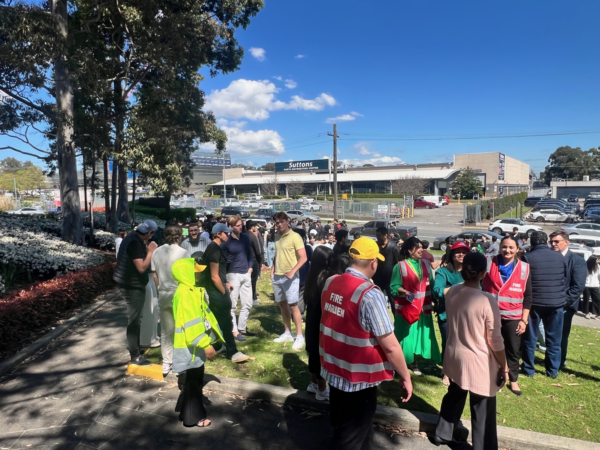 Wardens gathering evacuated staff at an outdoor assembly area